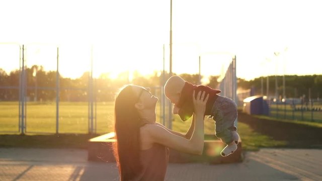 Mother plays with son near field at sunset. Slow mo