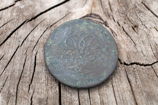 The old copper coin of the Russian Empire in 1757, the era of the reign of Elizabeth Petrovna. Against the background of cracked wood. 