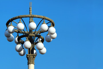 Retro style street lamp post with white ball lights against blue sky at daytime