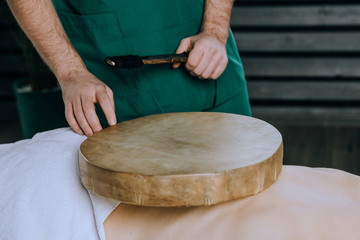 Massage the back of a woman with a tambourine. Nontraditional methods of medicine