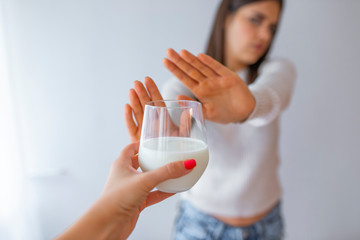 Close-up Of A Woman Rejecting Glass Of Milk At Home. Woman with milk allergy isolated. Lactose intolerance. Dairy Intolerant Woman refuses to drink milk