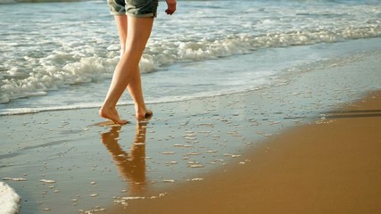 Close-up shot of bare feet. Woman walking across the sandy beach of Mediterranean sea. Greece. Slow motion. HD