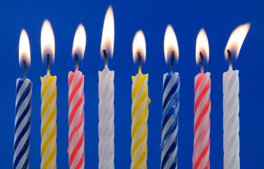 Burning colorful candles on blue background 