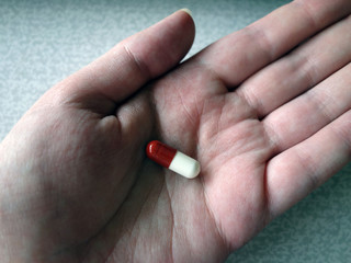 Hand with a red and white pill close-up