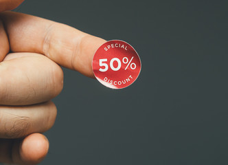 Man hand with glue sticked discount sale special price 50 percent red tags to be glued on goods during sale season - isolated gray background