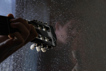Guitarra delante de ventana con gotas de lluvia
