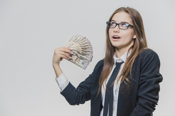 Happy excited young business woman is showing a pile of money, isolated on white background. Girl is satisfied by huge amound of bucks. Adorable businesswoman is smiling broadly wearing glasses with