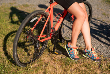 Fototapeta premium Young pretty woman holding bicycle outdoors at the park