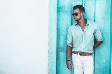 Portrait of a handsome young man in a casual clothing and sunglasses. Perfect hair & skin. Summer vacation concept. Outdoor shot.