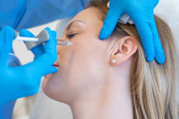 Close up of doctor doing beauty injection on the face of young woman in a cosmetology clinic