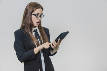 Attractive business woman is looking at the iPad, tablet being shocked, isolated on white background.