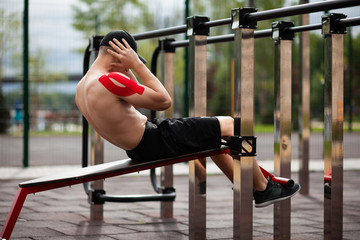 Young European athlete with injury is training outdoors. Kinesiology ( therapeutic, Kinesio,...