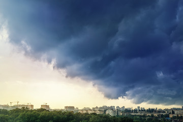 Cityscape covered with dramatic stormy dark clouds before heavy rain and thunderstorm. Natural disaster. Autumn seasonal weather forecast