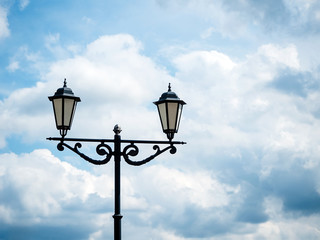 Fototapeta na wymiar black lantern in retro style against the sky with clouds