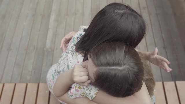The sad crying woman telling her story to her friend sitting outdoors. Cute student sharing the problem with her friend. Shooting from the top.