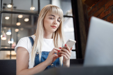 Young girl at cafe drinking coffee and using mobile phone. Online shopping