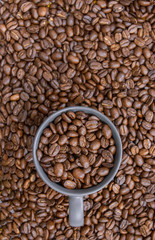 coffee beans in dark cup on mixed coffee beans background