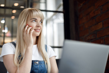 Fototapeta premium Young girl at cafe drinking coffee and using mobile phone. Online shopping