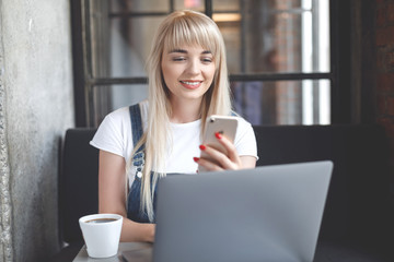 Young girl at cafe drinking coffee and using mobile phone. Online shopping