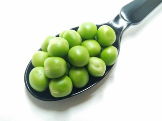 A picture of fresh green peas on black spoon