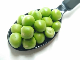 A picture of green peas on a black spoon