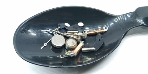 A picture of handwatch part's on a black spoon