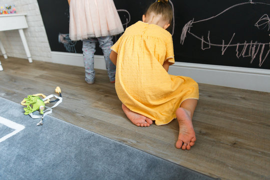 two caucasian little girls draw on the board with chalk