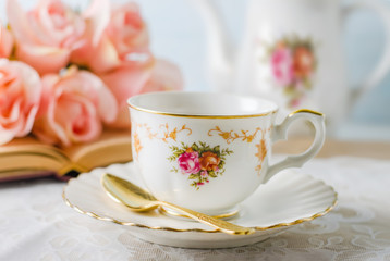 Cup of tea with book, teapot and rose flowers on blue background with vintage tone - Afternoon tea party concept