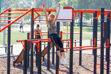 Happy smiling young woman at the sportsground outdoors. Successful training concept. Openair Gym & street Workout concept.