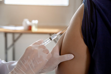 Female doctor injecting vaccine to a patient.