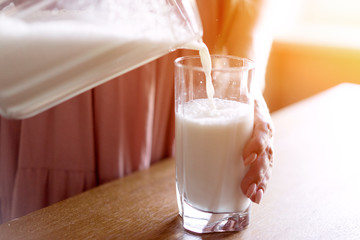 close-up, woman's hand pours milk into a glass from a decanter