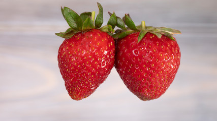 Red juicy strawberries hanging in the air. Seasonal berries.