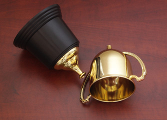 Fototapeta na wymiar Broken golden trophy cup on wooden background, loose and unlucky concept