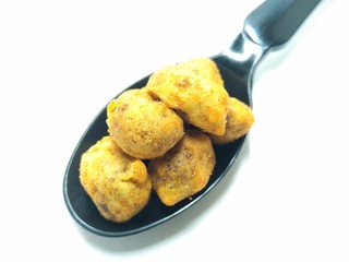A picture of spicy peanuts on a black spoon