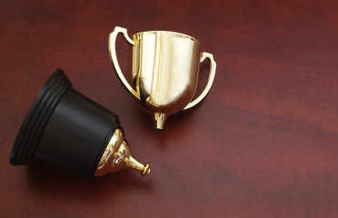 Broken golden trophy cup on wooden background, loose and unlucky concept