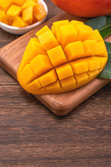Fresh Mango - Juicy chopped mango cubes on wooden cutting board and rustic timber background. Tropical summer concept. Close up, macro, copy space.