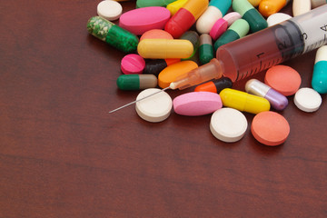 Drugs, pills and syringe on wooden table with room for text, pharmacy and medical concept.