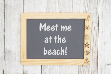 Meet me at the beach text on a chalkboard with nautical objects