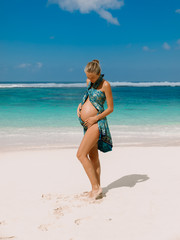 Beautiful pregnant woman expecting baby at tropical beach