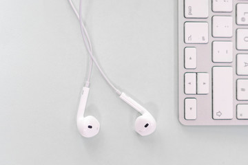 inEar Kopfh&ouml;rer neben einer kabellose Tastatur liegend auf einem B&uuml;rotisch