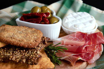 still life crispy pizza, prosciutto, cheese ,green olives, dried tomatoes on a wooden plate.