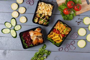 black plastic food boxes with grilled chicken, bean and vegetables
