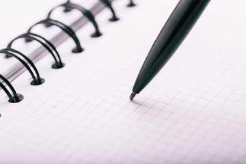 Opened notepad in a cage with an automatic plastic ballpoint pen close-up. toned