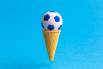 Soccer ball in ice cream cone abstract isolated on blue.