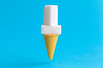 Sugar cubes in ice cream cone abstract isolated on blue.