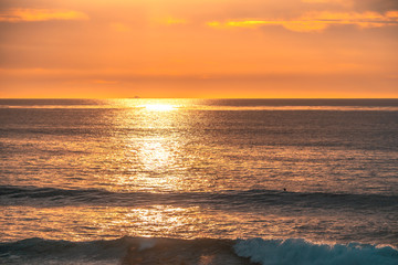 Lonely surfer is waiting for wave on beautiful sunset. Leisure, active sports concept