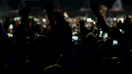 Concert fans. Audience with raised hands at music festival dancing during musical group performance. UHD, Slow motion.