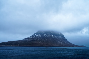 Kirkjufell mountain in Iceland with mystical cloudy atmosphere from alternative perspective as usual