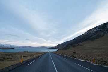 On the road along a lake in Iceland with clouded sky and mystical atmosphere in winter
