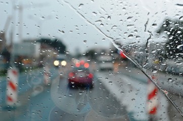 Inside car when rainning, Road view wtih restriction signs through car window with rain drops. Drizzle on the windshield.